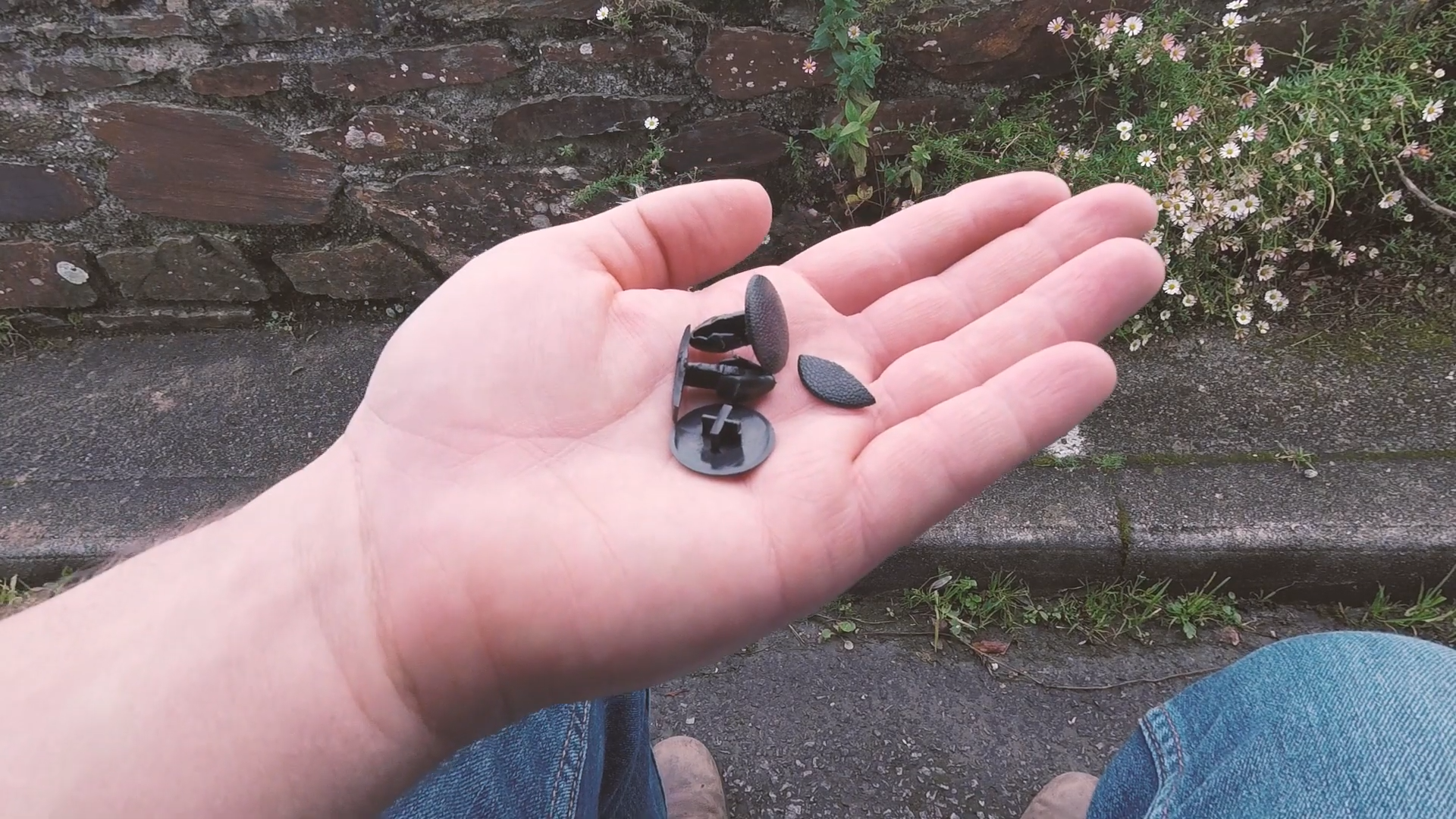 A hand holding a selection of Nissan NV200 panel clips, with some of them broken
