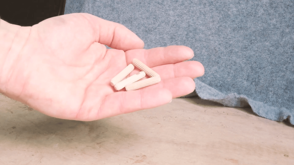 A hand holding 4 wooden dowels