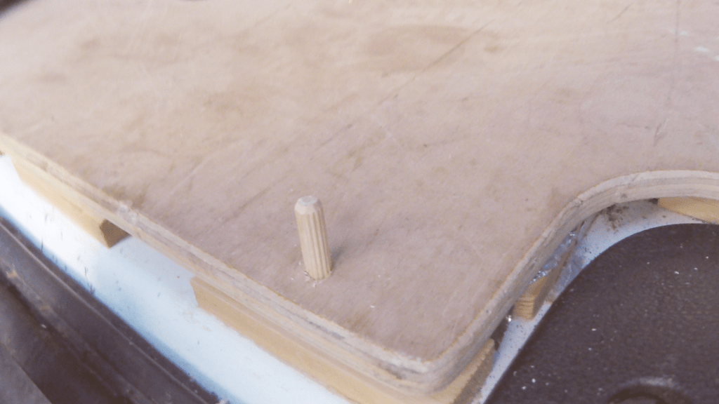 A dowel sticking out of the wooden plywood floor at the back edge of the van