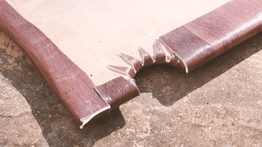 Close-up of the vinyl edge stuck to the underside of the plywood van floor