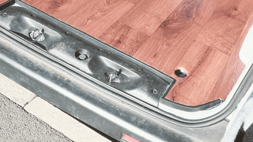 The black rubber l-section at the van floor back door edge