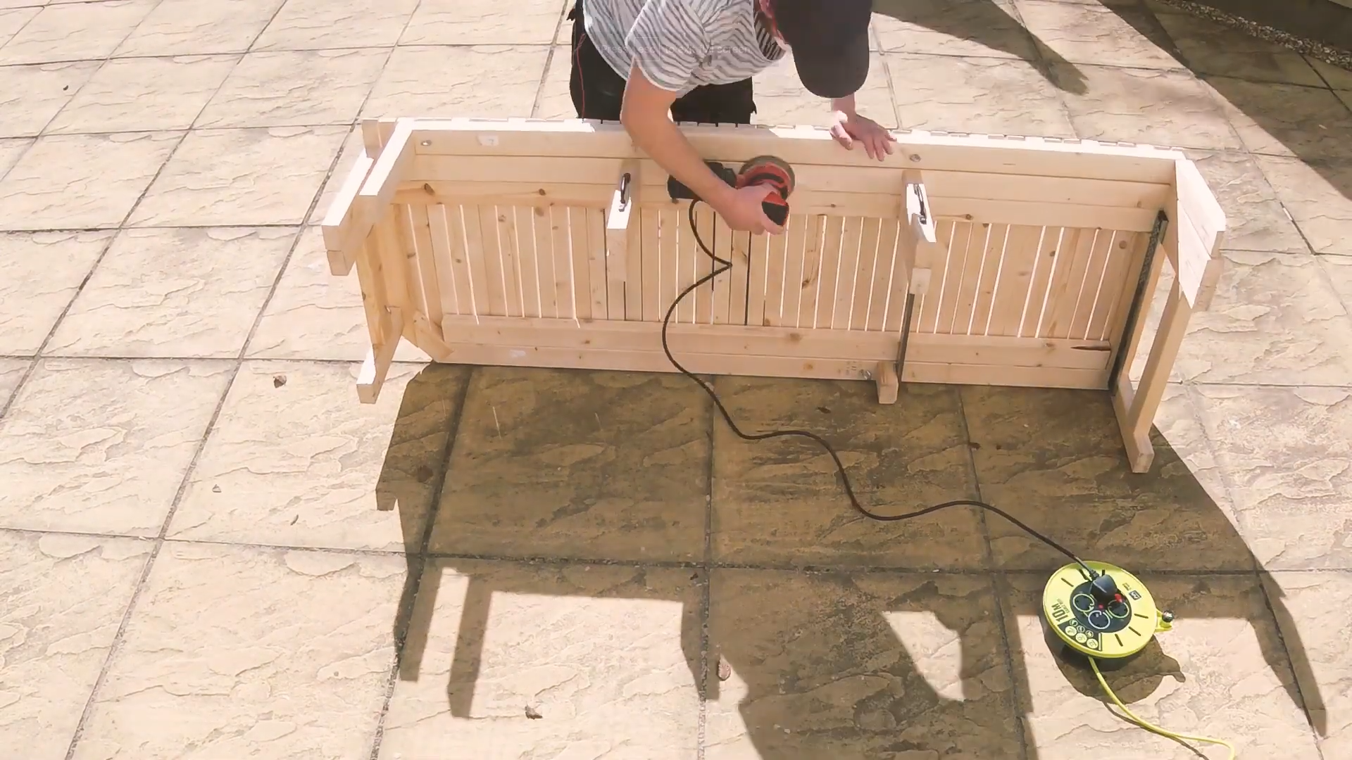 A man sanding down a van bed, with the bed on its side