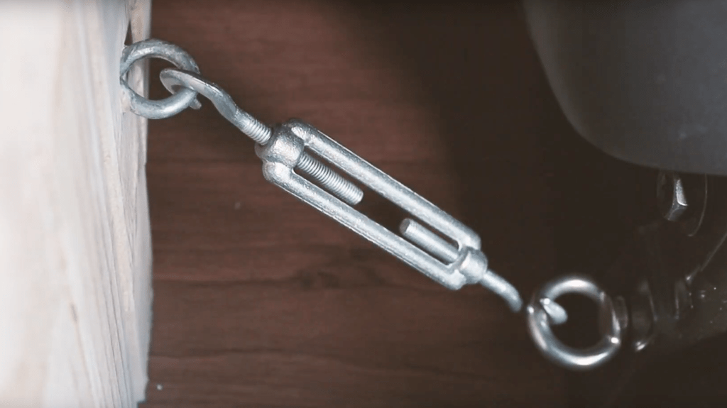 A turnbuckle attached to a metal eye on a van bed and a metal ring on a van front seat