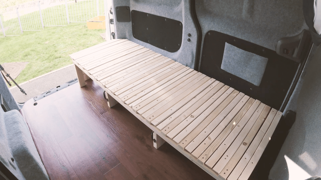 The wooden bed positioned in the back of the van