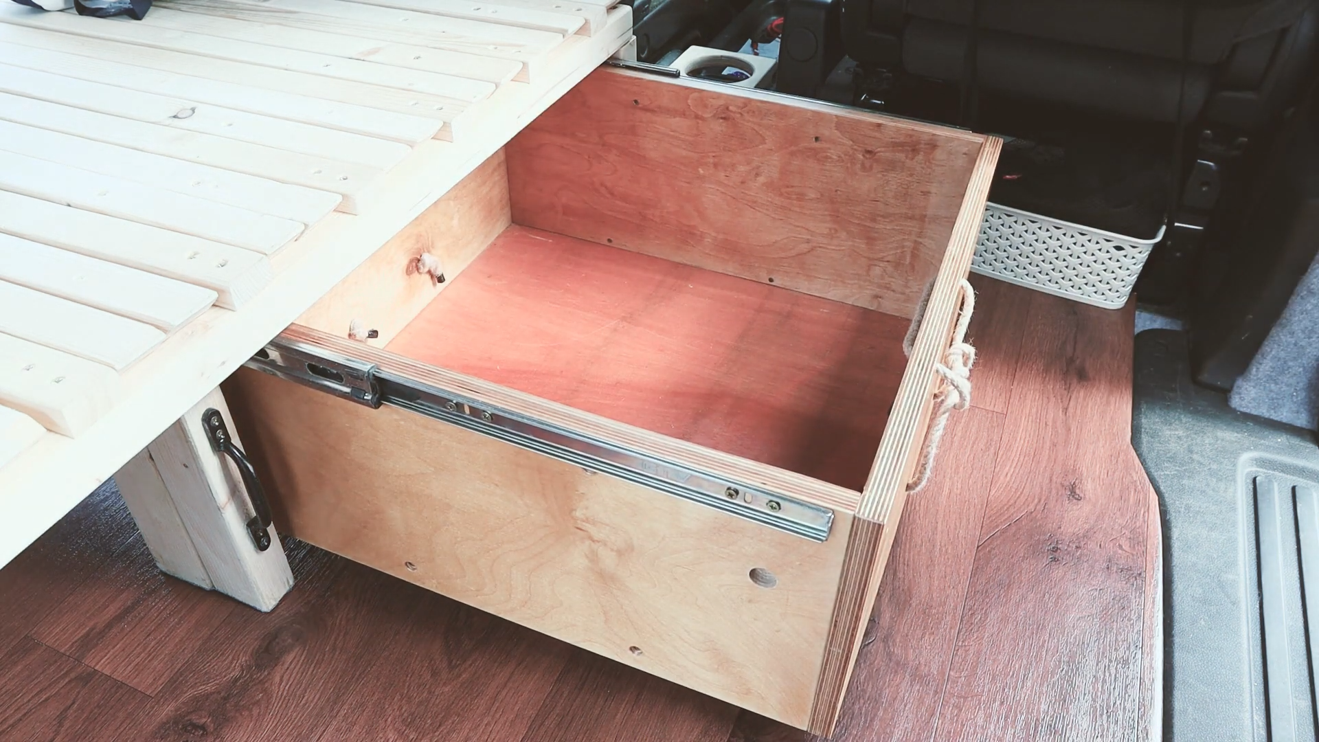 A open draw made of plywood extending out from under the van bed