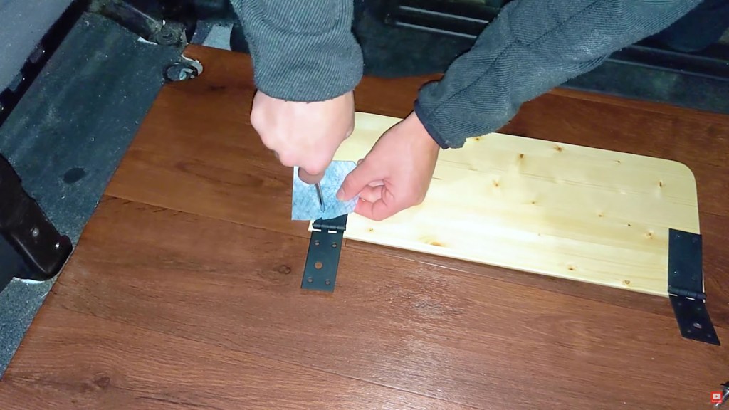 Screwing the hinges in place, using a cloth to prevent damage