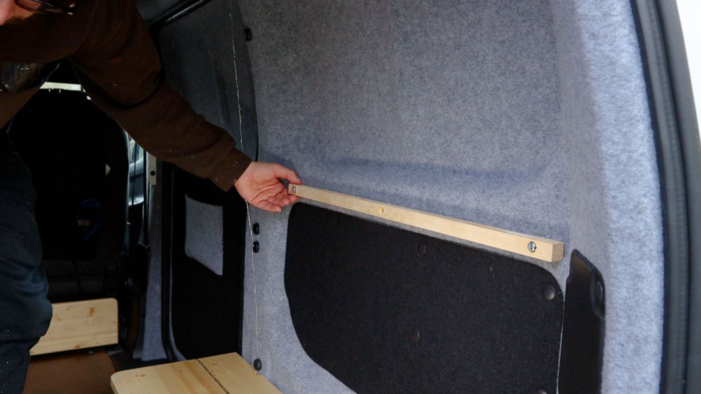 Length of wood bolted to the van wall