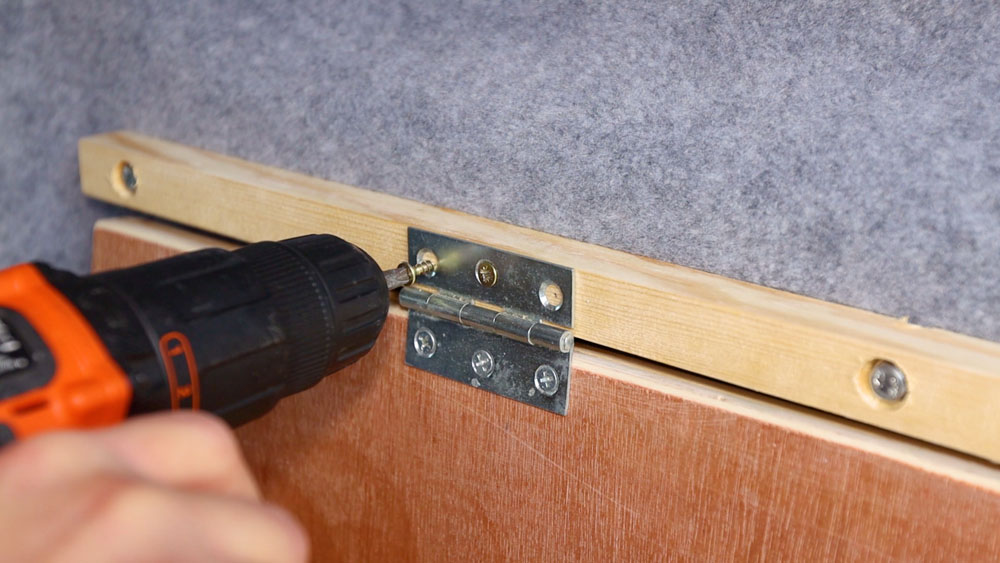 Attaching the hinges on the table into the wood on the van wall
