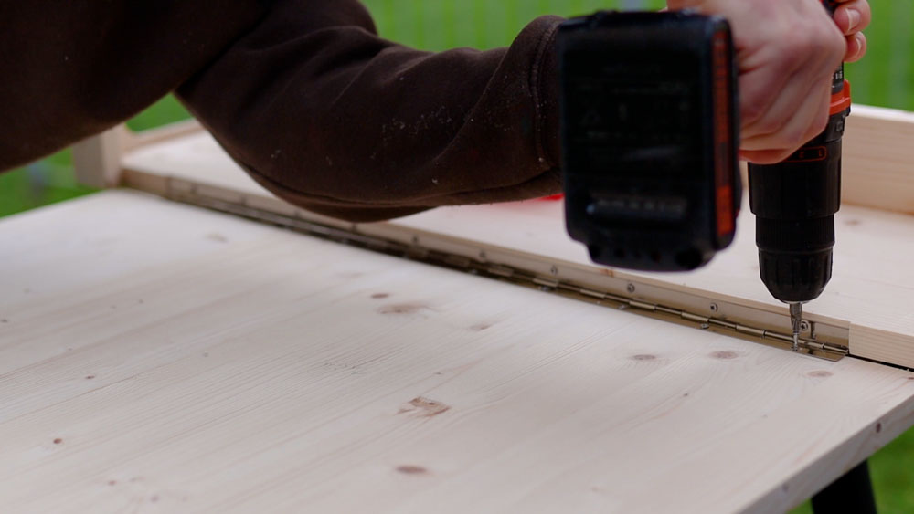 Screwing the piano hinge to the table