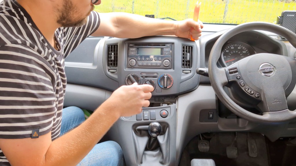 Prying off the upper stereo trim on a Nissan NV200 dashboard
