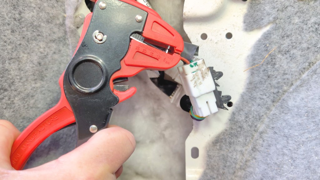 Using wire strippers to expose some wire on the red reversing camera wire